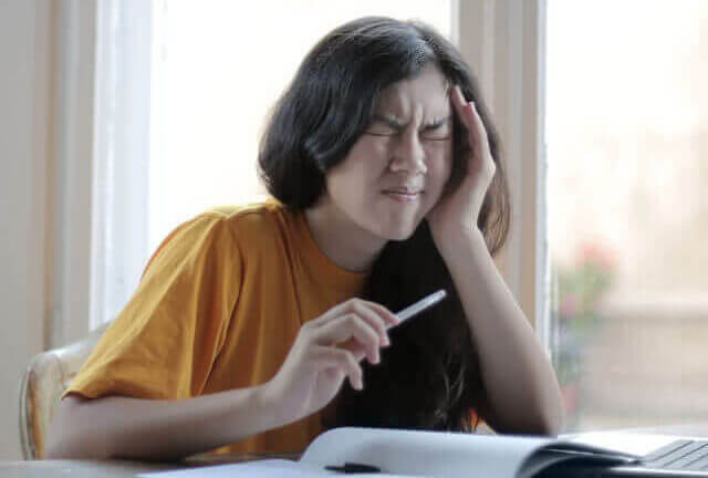 teenager pressing fingers to her temple in pain